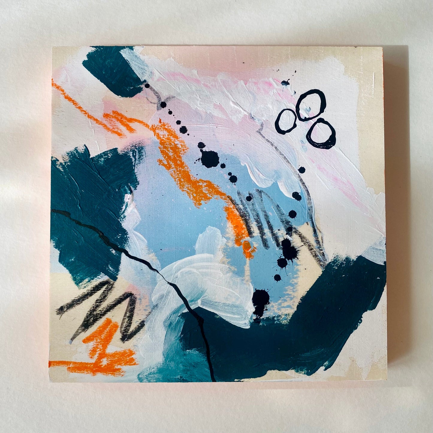 Abstract painting with blue, orange, and black on a beige background