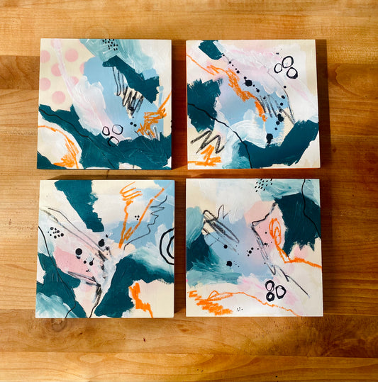 Four abstract art prints on a wooden surface